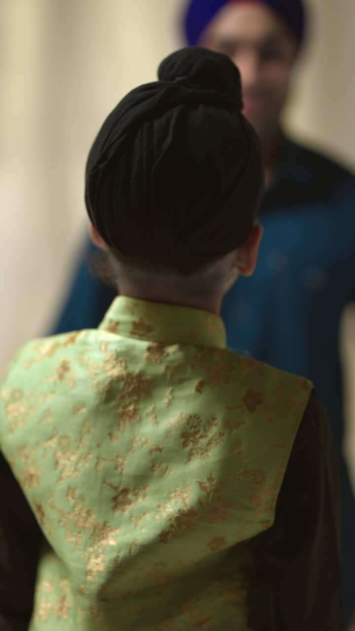 una toma de estudio de video vertical de un padre sikh amoroso abrazando a su hijo, ambos con turbantes contra un fondo plano 2