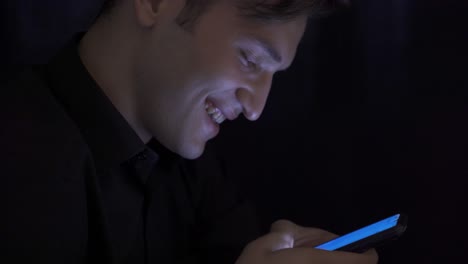 joven enviando mensajes de texto en primer plano con el teléfono inteligente y mirando.