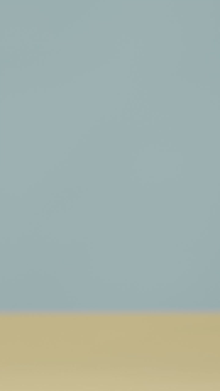 노란색 배경에 얼음과 함께 차가운 음료를 내려 놓는 손으로 수직 여름 휴가 개념