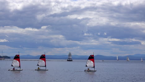 four small sailboats with a lighthouse in the background