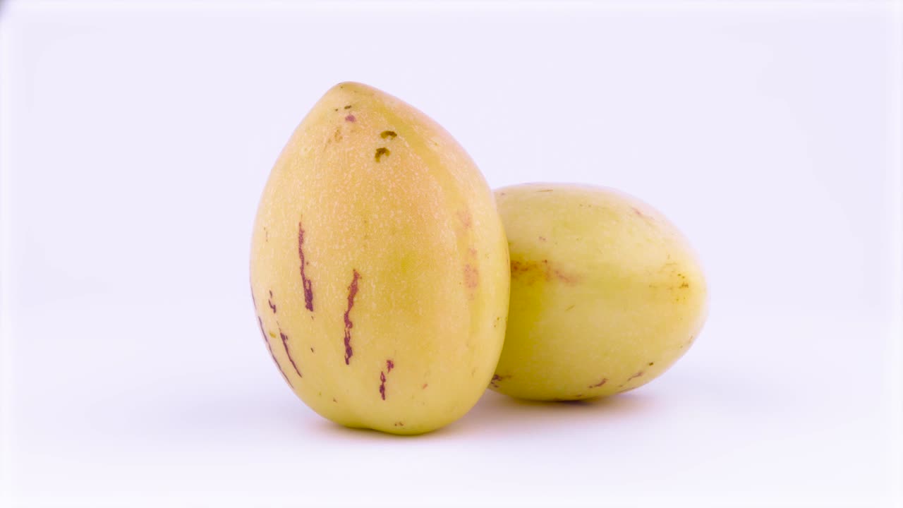 dos frutos maduros de pepino amarillo. girando en la mesa giratoria. aislados en el fondo blanco. primer plano. macro.