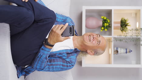 Vertical-video-of-The-old-man-texting-on-the-phone-laughs.