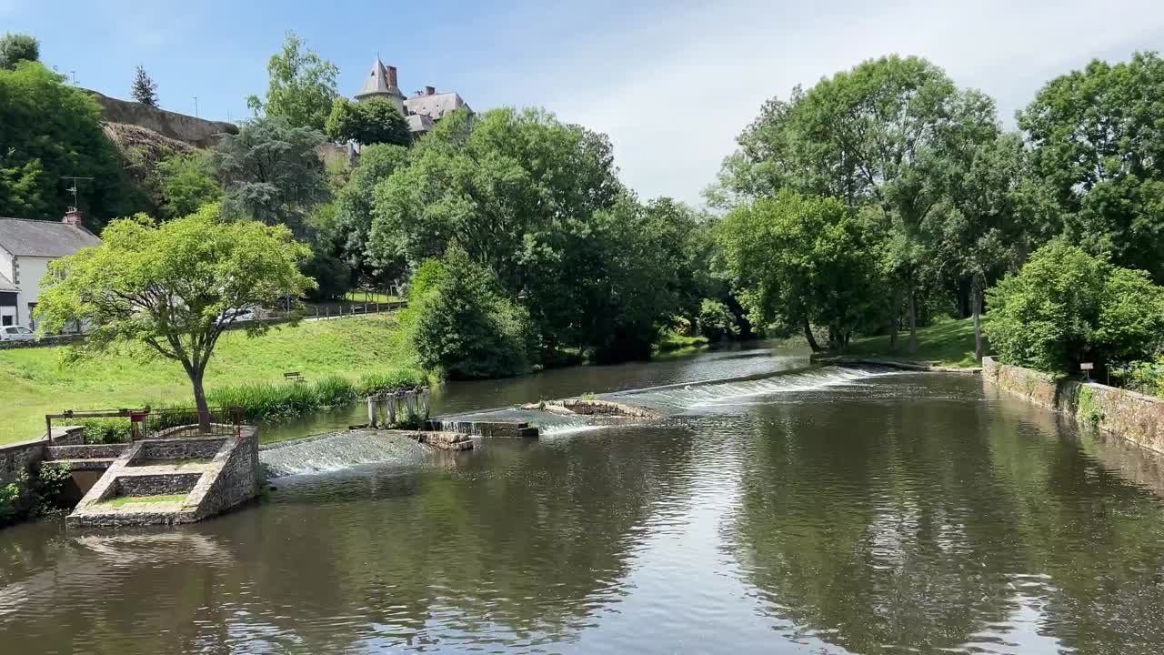 Weir on a river with calm water surrounded by trees,