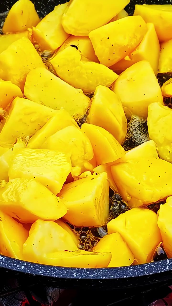 Biter av gul squash småkoker forsiktig i en panne, og skaper en varm og innbydende scene.