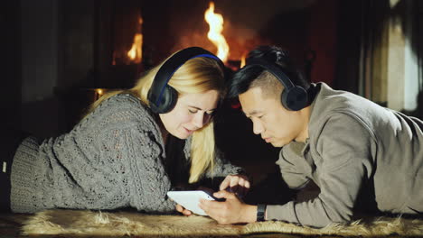 Young-Couple-Sharing-Tablet-By-Fireplace-02