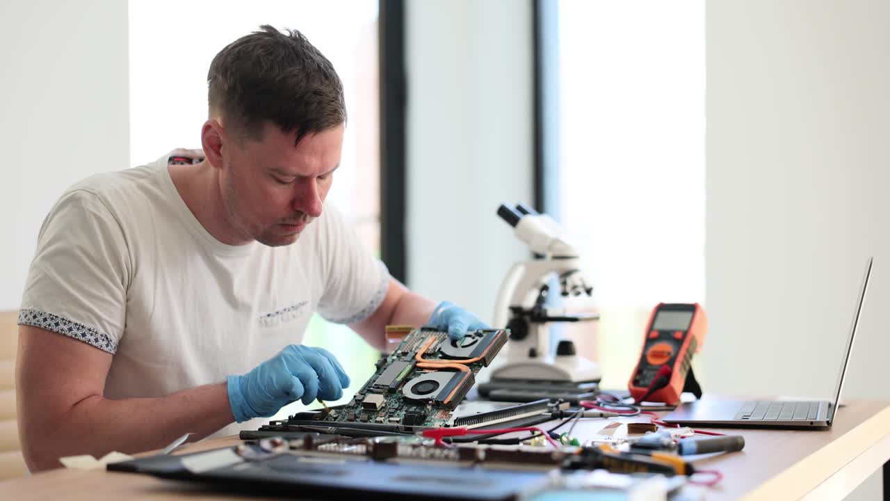 Technician working on a laptop motherboard or computer hardware