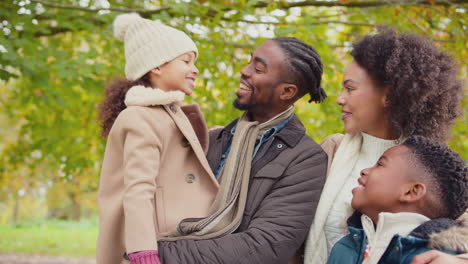 portrait of smiling family with parents with children on walk through autumn countryside together - shot in slow motion