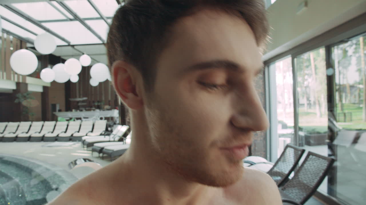 호텔 스파에서 비디오를 녹화하는 행복한 남자. 럭셔리 스파에서 카메라를 말하는 행복한 남자