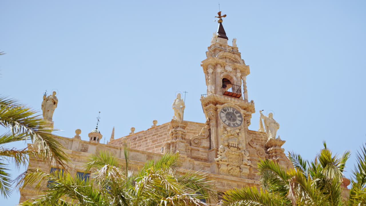 Low angle view of the Church of Santos Juanes surrounded by palm trees on a blue sky background in Valencia, Spain