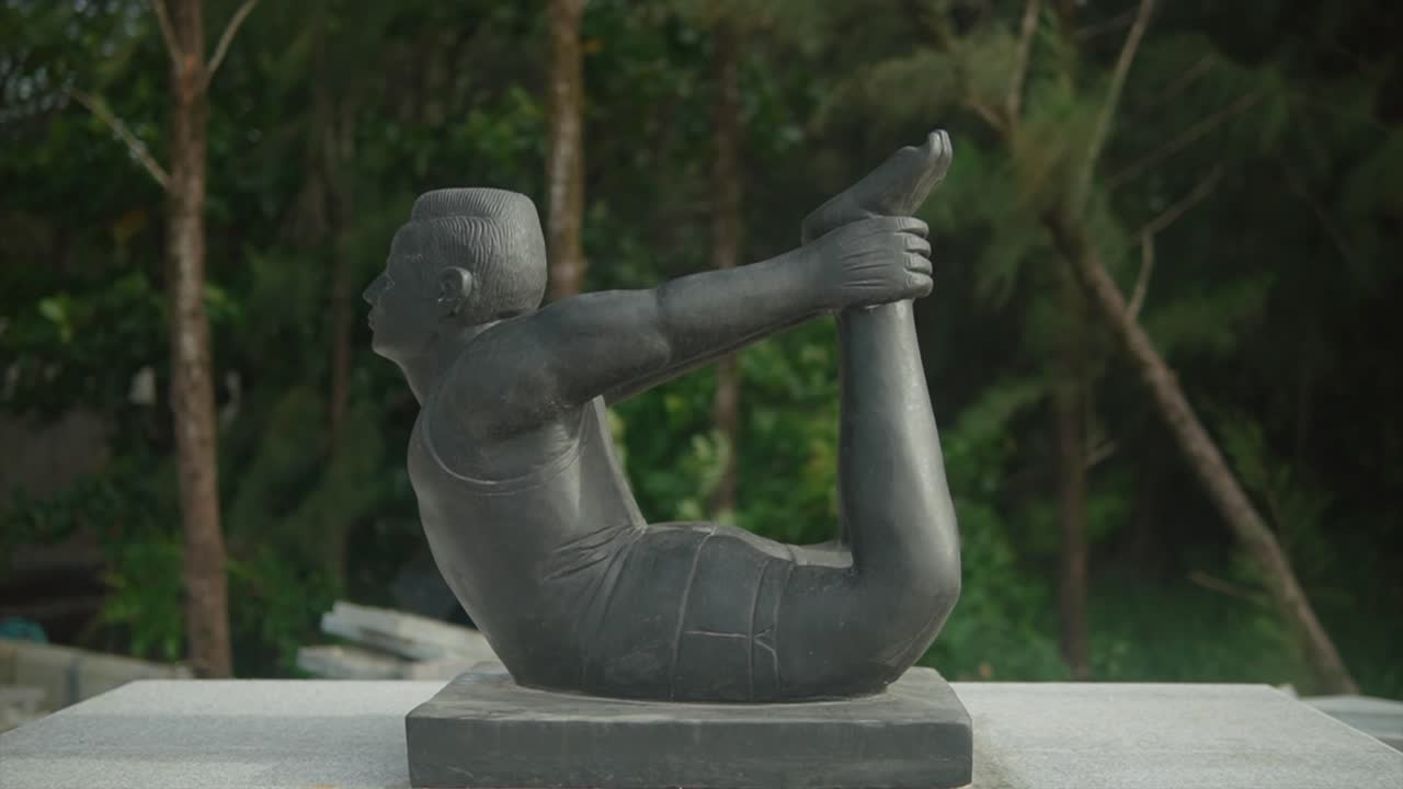 다누라사나 요가 자세 로 발 을  ⁇ 고 있는 남자 의 동상