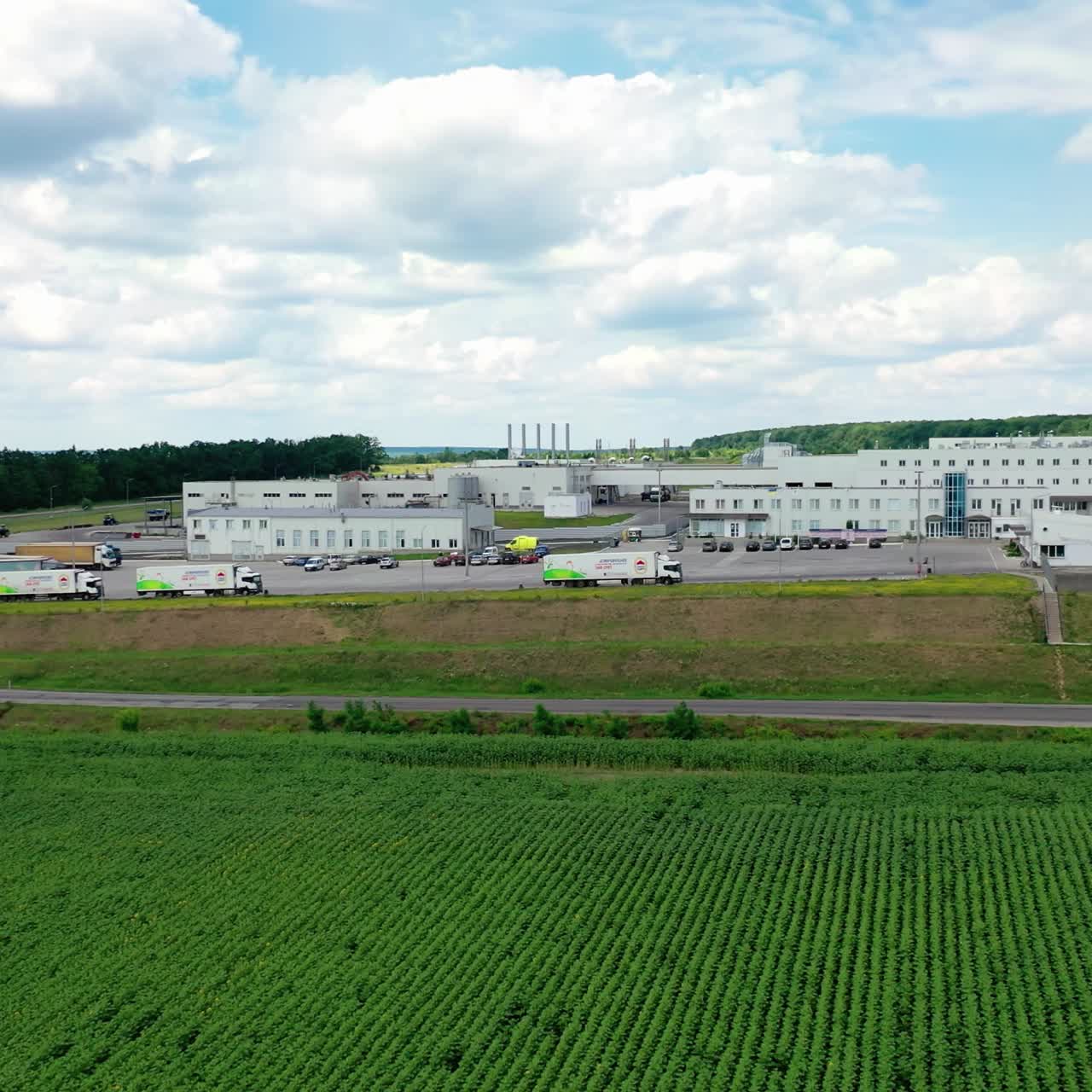 Aerial view of modern storage warehouse with many trucks on parking lot. Industrial zone on city suburb