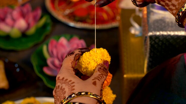 Decorazione di Diwali - Donna che prepara una ghirlanda con fiori freschi.