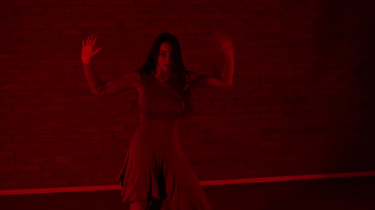 Danzatrice emotiva e carismatica che balla sotto un'illuminazione rossa.