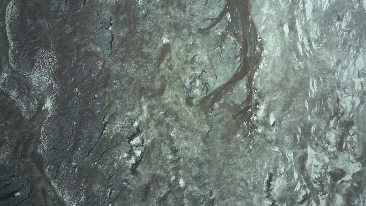Ascending reveal over Salar de Quisquiro silver salt crust with intricate dark cracked patterns and branching sediment channels resembling abstract natural artwork. Salar de Quisquiro, Chile