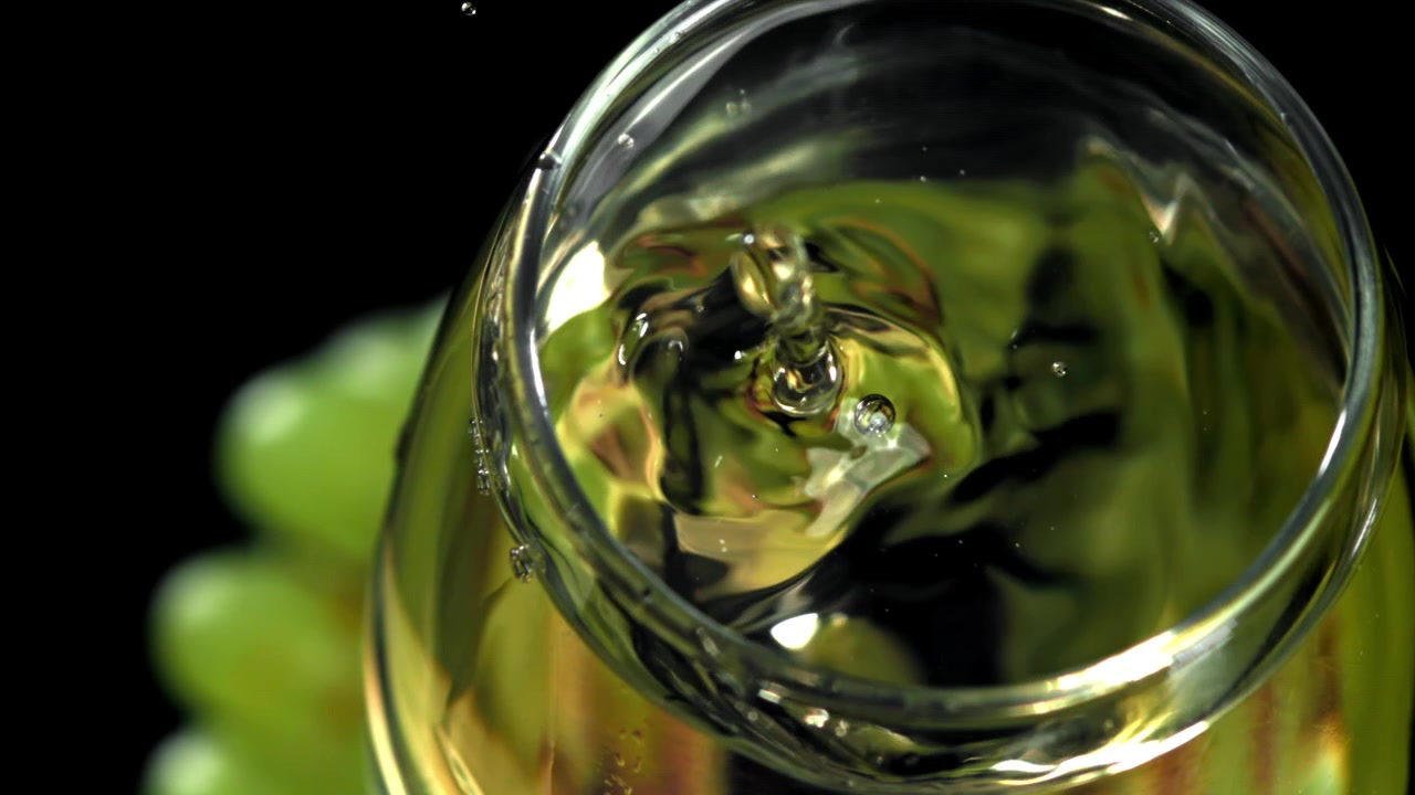 White Wine Drop Splashing in Glass with Green Grapes