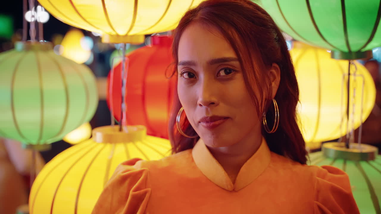 베트남 여성의 느린 동작 초상화. 전통적인 노란색 드레스를 입고, 직선 눈선으로 랜턴 조명을 고 있다.