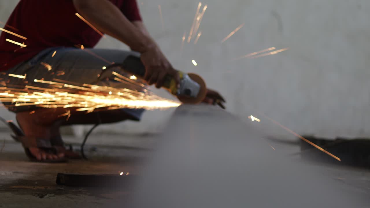 los trabajadores están cortando hierro usando un molinillo de mano, las chispas del molinillo están salpicando por todas partes