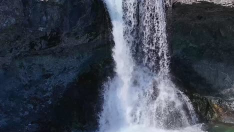 waterfall skutafoss is showcased in this outstanding photograph, which masterfully captures the tranquil interaction between the waterfall and the pebbles