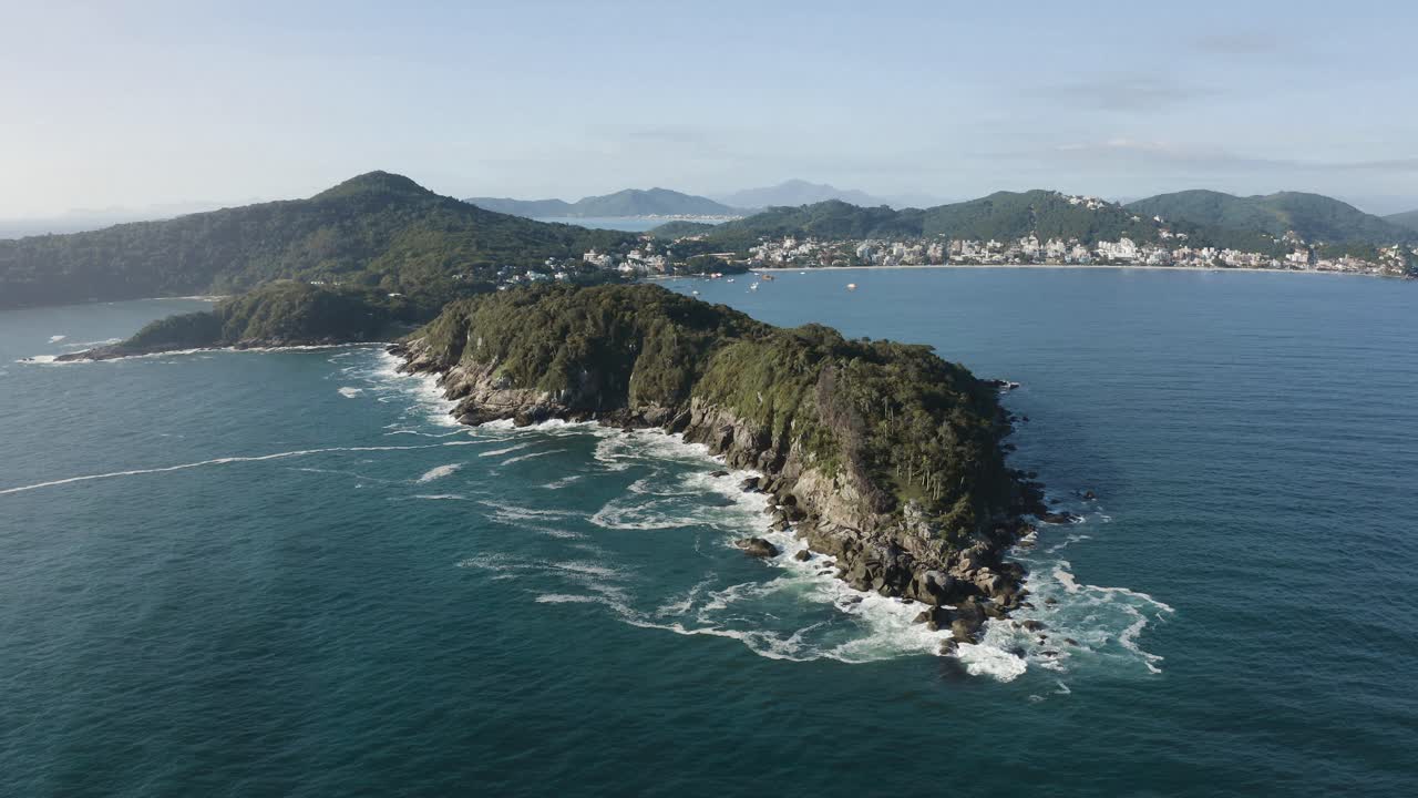 Epica ripresa cinematografica con drone che avanza sull'oceano di una costa brasiliana, con alte scogliere, giungla e acqua blu intenso.