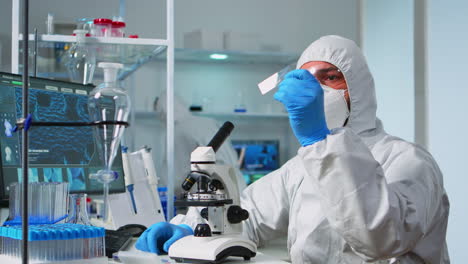 Scientist-in-ppe-suit-placing-a-slide-on-specimen-stage