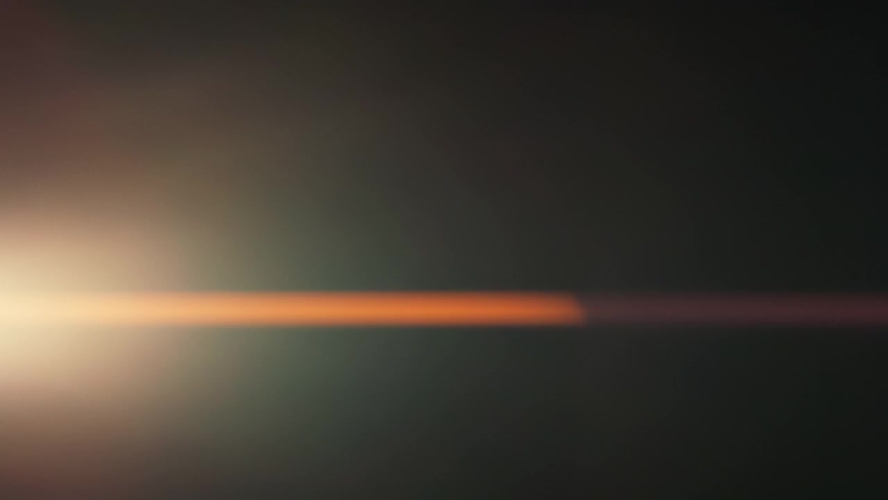 Bagliori orizzontali di lente anamorfica che si muovono su uno sfondo scuro.