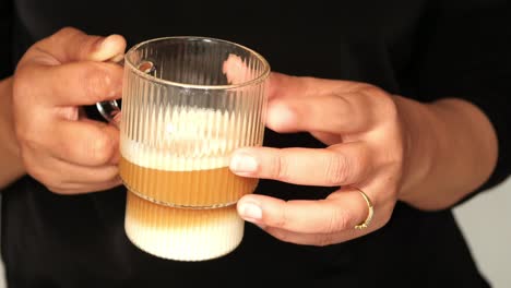 woman holding a glass latte