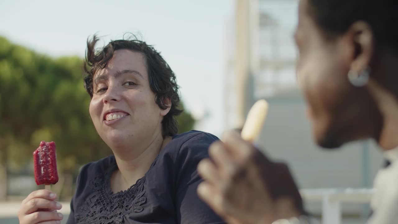 mujer joven feliz comiendo helado y hablando con un amigo masculino