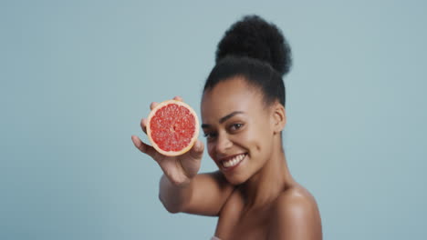 portrait attractive young mixed race woman holding grapefruit smiling enjoying natural healthy skincare essence beautiful female with perfect complexion on blue background