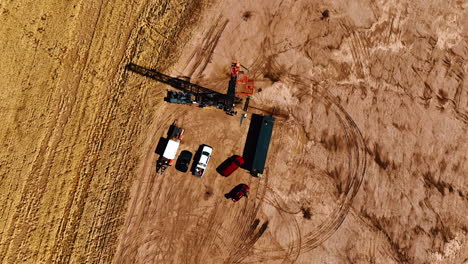 circling high above the little site for drilling oil. a few trucks with the equipment for resources production.
