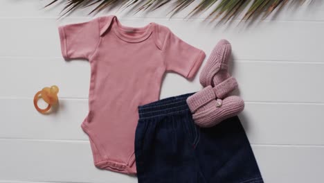 video of pink baby grow, shorts, dummy and pink booties with copy space on white background