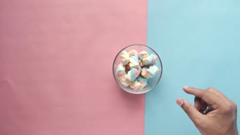 hand reaching into a bowl of colorful marshmallows