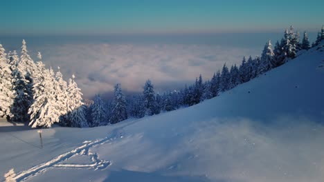 experience the enchanting winter drone journey as snowy peaks meet vibrant sunset skies, revealing a serene path through misty mountains