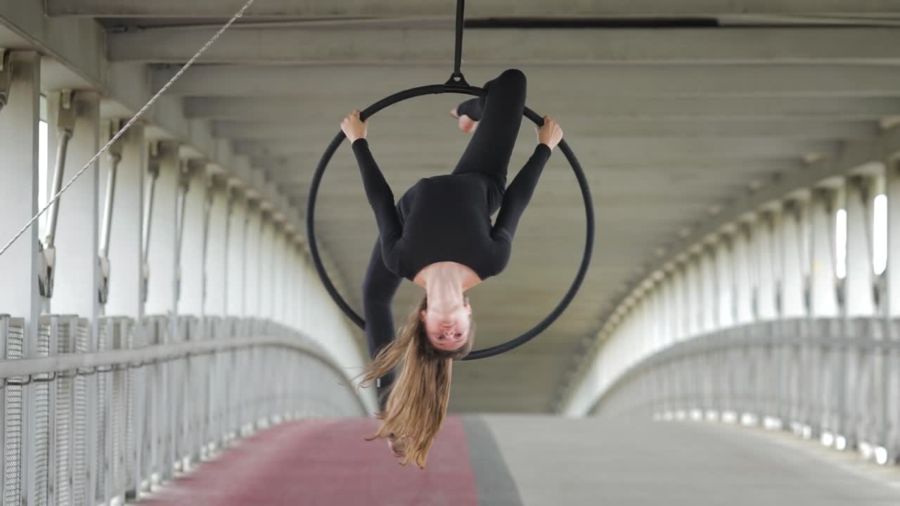 Urban female acrobat balancing on a hoop in the street at daytime