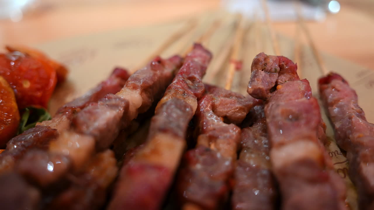 Vista dettagliata di spiedini di carne alla griglia su bastoncini di legno con profondità di campo ridotta