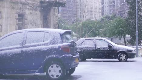 two parked cars in urban inner city jerusalem city with snow falling, slow motion