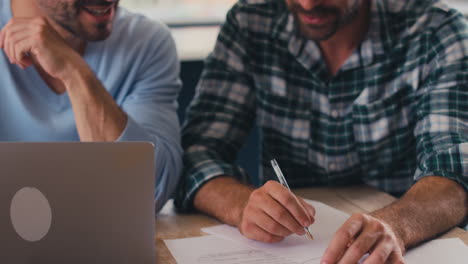 Same-Sex-Male-Couple-Using-Laptop-At-Home-To-Check-Domestic-Finances