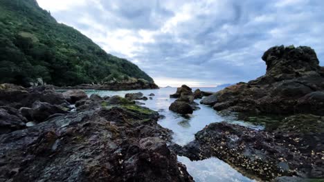 Timelapse-De-Agua-Subiendo-Y-Bajando-En-Una-Bahía-Rocosa-Mientras-La-Marea-Cambia-Y-Las-Nubes-Pasan-En-Peach-Cove,-Nueva-Zelanda