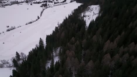 Aerial-view-of-winter-drift-race-track-near-hillside-with-dark-forest