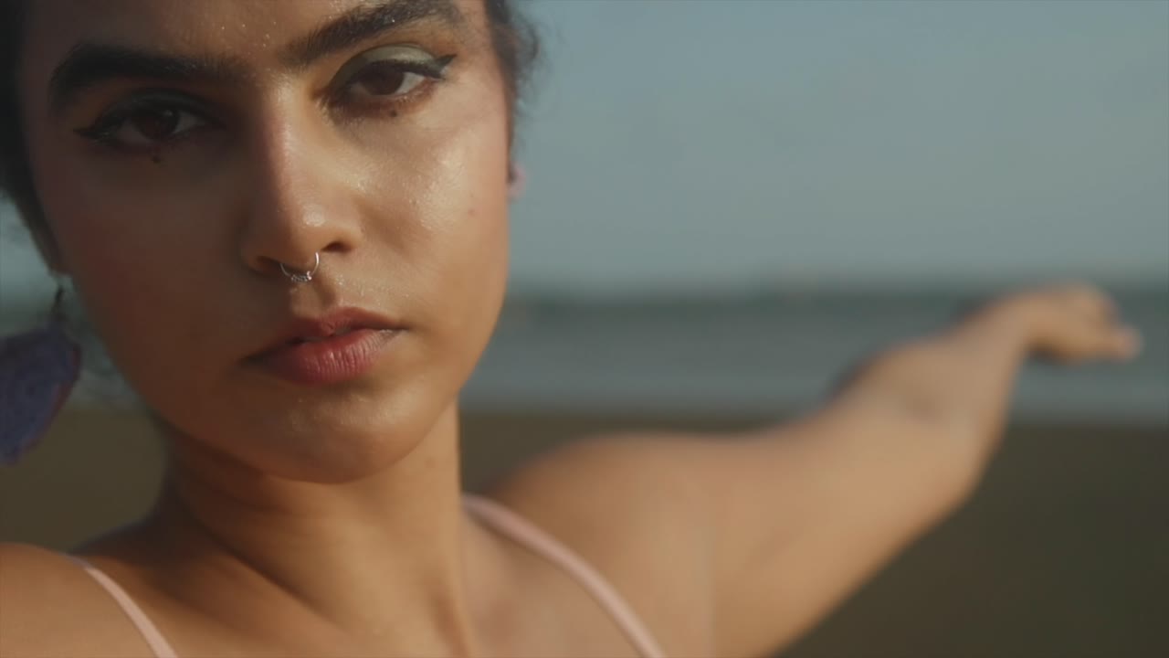 Primo piano del braccio di una bella donna che esegue uno stretching yoga in spiaggia. Giovane e bella donna indiana che allunga braccia e mani per il riscaldamento prima di un allenamento sportivo.
