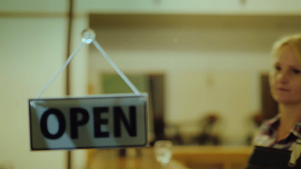 una mujer cierra la tienda voltea un cartel con la inscripción cerrada al final de la jornada laboral