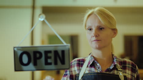 a woman closes the store flips a sign with the inscription closed the end of the working day