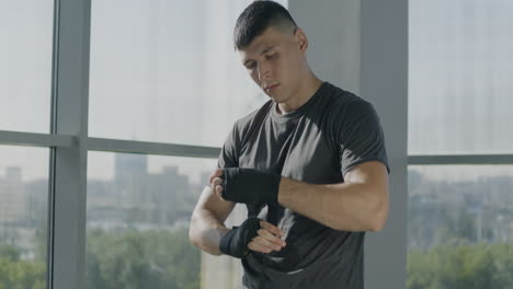 man putting on boxing hand wraps in gym