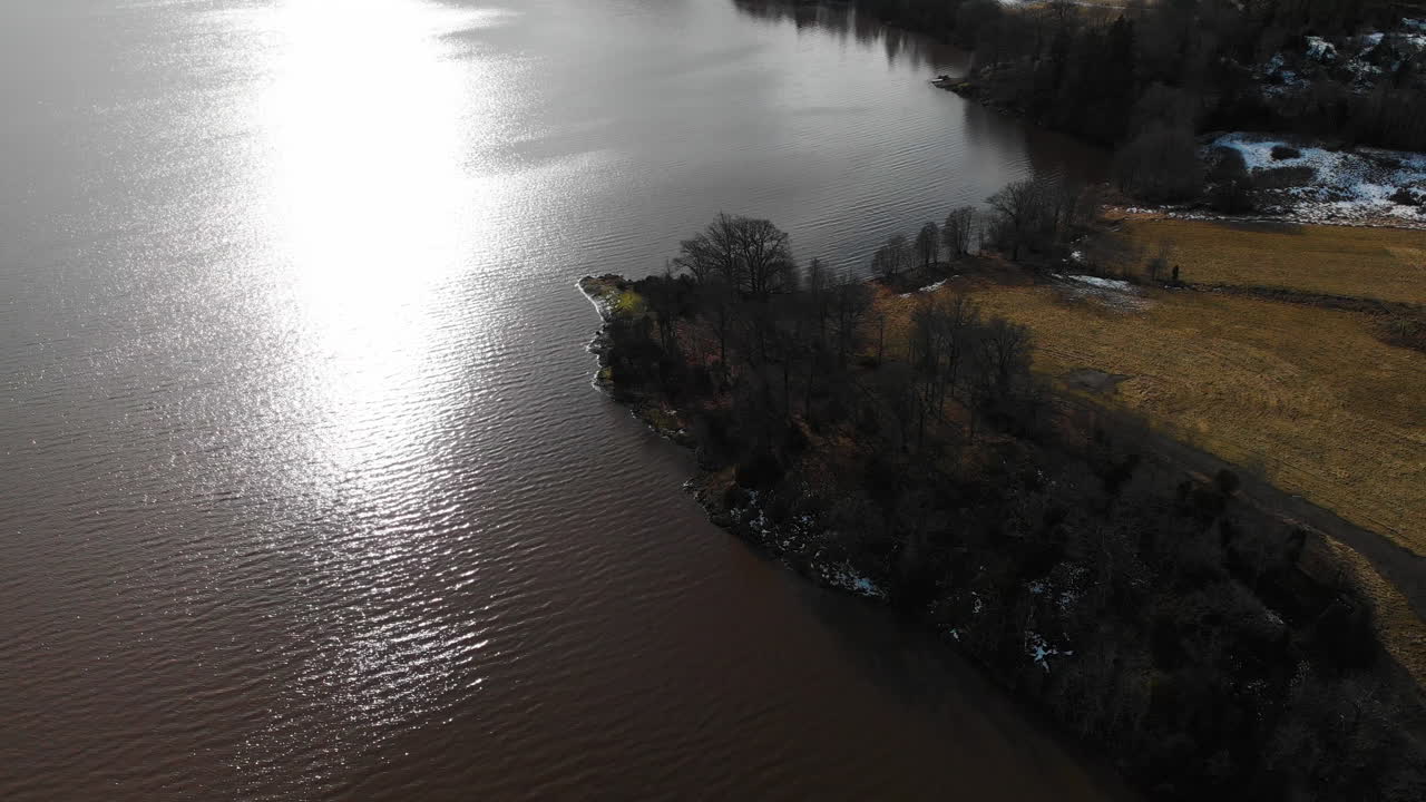 늦은 겨울에 시골 지역의 잔잔한 호수 물에 반사되는 햇빛