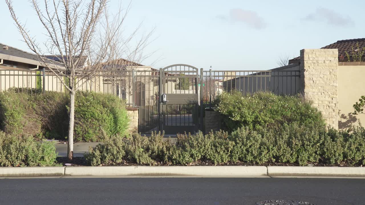 Un pittoresco cancello di quartiere adornato con vegetazione, sullo sfondo di un cielo nuvoloso a Roseville, California.