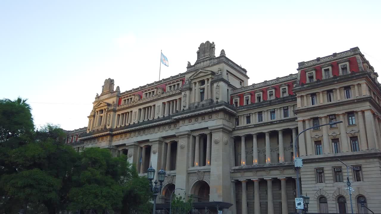 Palace of Justice, national building, Argentine flag waves over sunset skyline, establishing shot of eclectic Neoclassical architecture