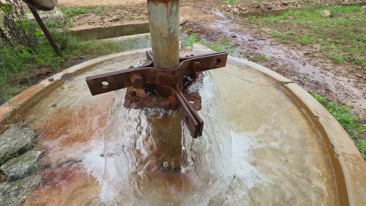 water gushing freely from a borewell without any motor or pump. The underground pressure is strong enough to push the water up to the surface on its own