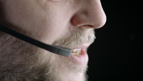 lower face against black background, man speaks into phone headset