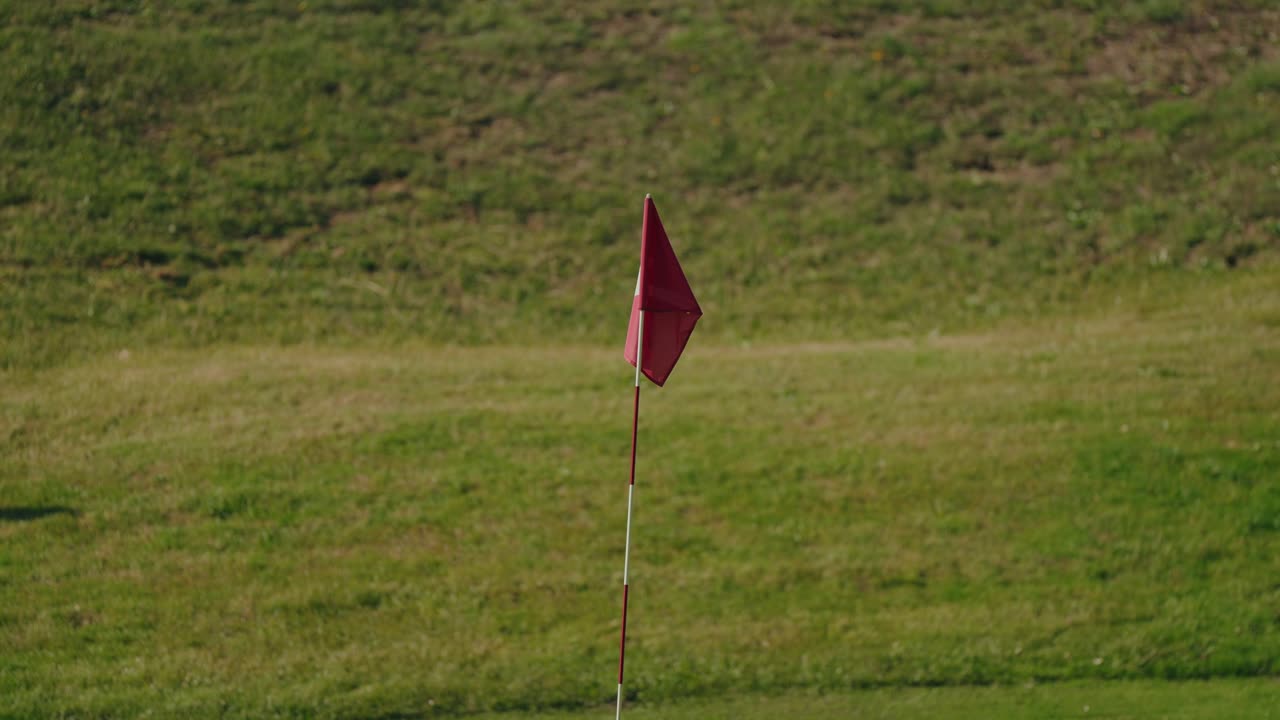 Golfhulsflag plantet på grønt græs i roligt morgenlys