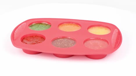 congelar batido de frutas en molde de silicona sobre un fondo blanco. vista lateral. movimiento en bucle. rotación 360.