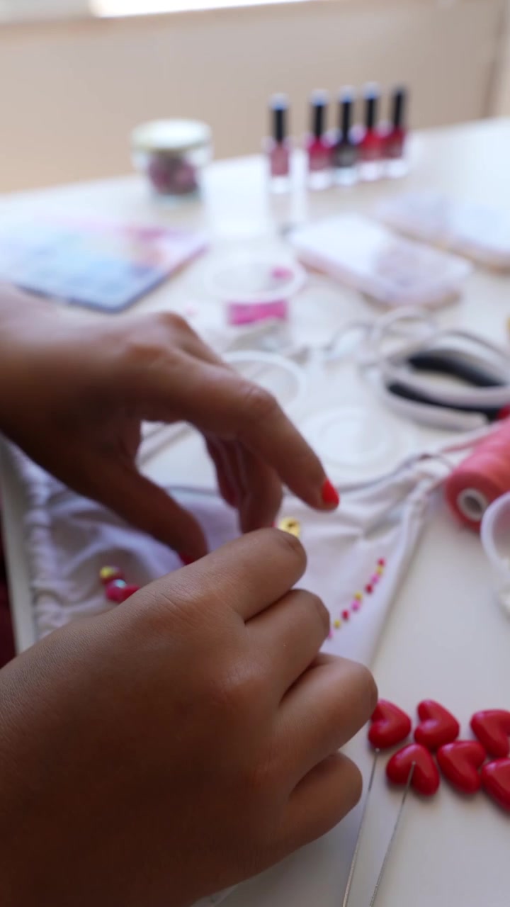 Persona che decora tessuto bianco con perline a forma di cuore